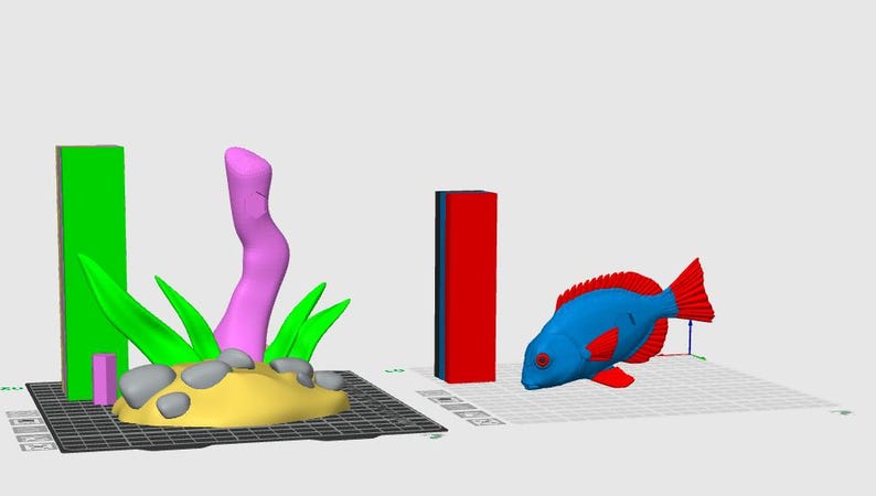 Pu&ograve; includere: Una scena renderizzata in 3D con un pesce blu e rosso, una base di sabbia gialla con erba verde e rocce grigie e una struttura rosa simile al corallo. Sono presenti anche due forme rettangolari, una verde e una rossa.