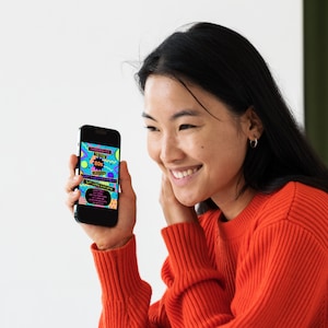 May include: A person is holding a smartphone displaying a colorful invitation to a "Throwback to the 80s" party. The invitation features a retro design with geometric shapes and bright colors.