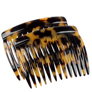 May include: Two tortoiseshell hair combs with a curved shape and a row of teeth. The combs are made of a brown and black plastic material.
