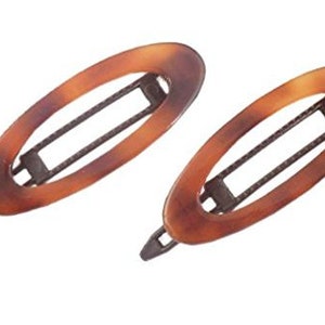 May include: Two brown tortoiseshell oval hair clips with a black metal bar in the center.