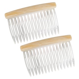 May include: Two clear plastic combs with wooden handles. The combs have a curved shape and are designed for styling hair.