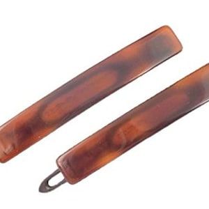 May include: Two brown tortoiseshell hair clips with a metal spring clip. The clips are rectangular and have a smooth, glossy finish.