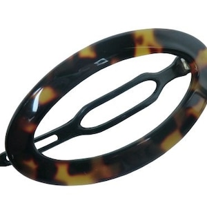 May include: A tortoiseshell oval hair clip with a black metal spring clip.