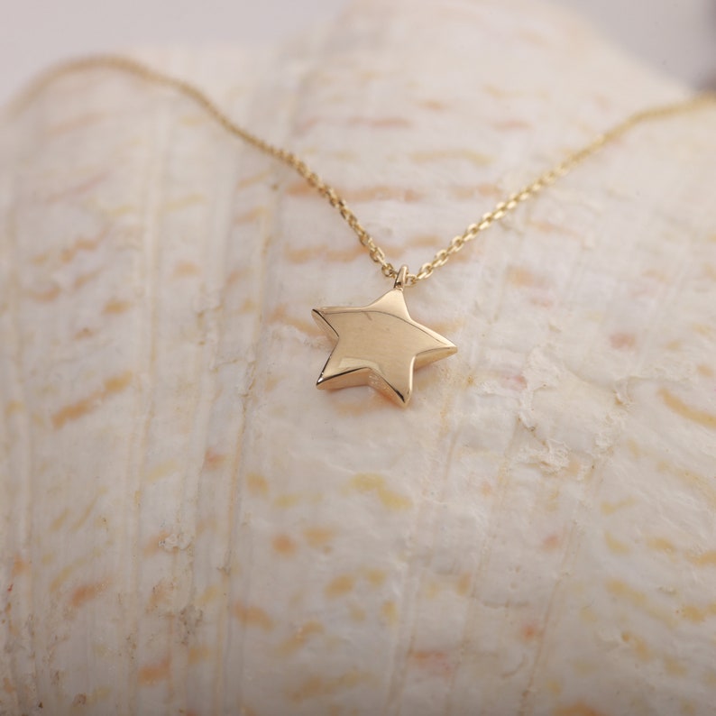 14K gold star pendant necklace with a fine chain. It has a curved and shiny surface. You can order this star shaped necklace in 3 different color options.