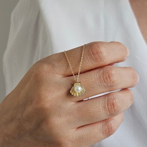 14K Gold Pearl Necklace with a fine chain. There is a round pearl in a gold shell pendant.