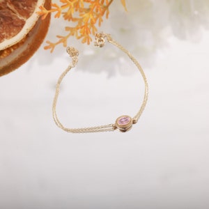 Our product is a tiny june birthtstone morganite pendant bracelet with double fine chains. There is an oval cut morganite gemstone in the center of a gold slot.