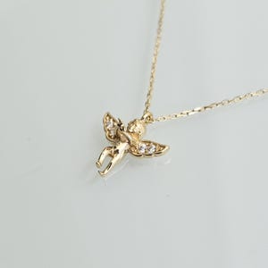 May include: A gold necklace with a small cherub pendant adorned with clear cubic zirconia stones.