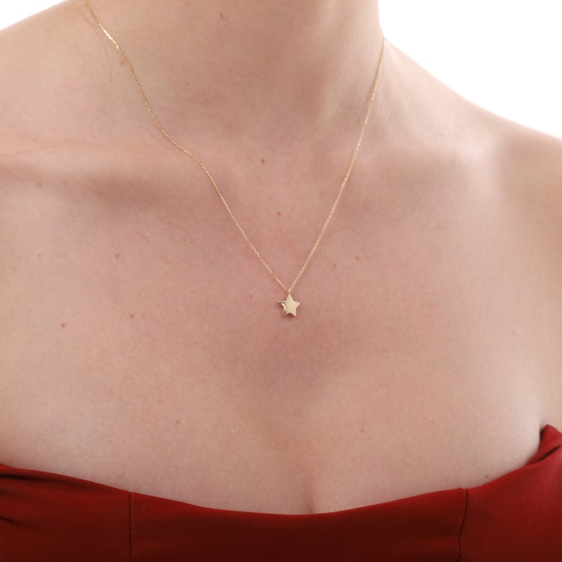 May include: A delicate gold chain necklace with a small, star-shaped pendant.