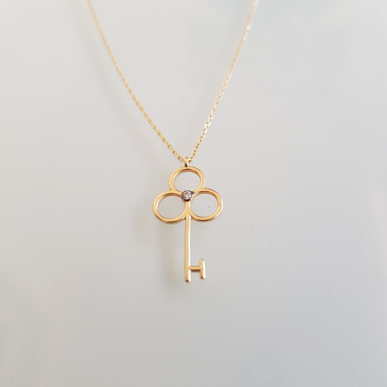 14K dainty gold key necklace with a fine chain. There is a little zircon in the middle of the handle of the key. It is available in three different color options.