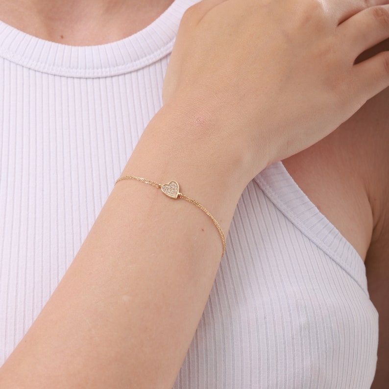 14K solid gold heart shaped pendant bracelet with double fine chains. The item in the photo is yellow gold and there are white zircon gemstones on the front surface of the heart. You can order it in white or rose gold as well.