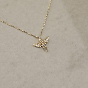 May include: A gold chain necklace with a small, detailed angel pendant adorned with tiny clear cubic zirconia stones.