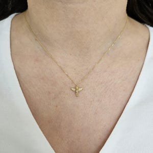 May include: A gold chain necklace with a small angel pendant. The angel has wings and a halo.