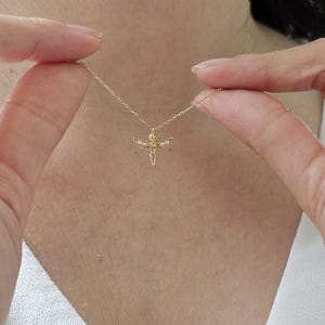 May include: A gold chain necklace with a small angel pendant featuring clear gemstones. The angel has outstretched wings.