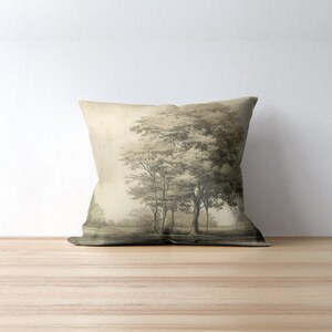 May include: A throw pillow featuring a sepia-toned image of trees in a woodland setting. The pillow is a light beige colour.