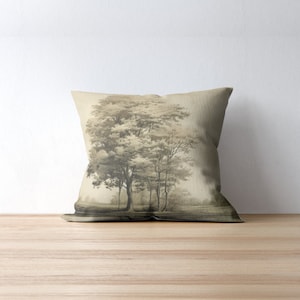 May include: A throw pillow featuring a sepia-toned image of a group of trees in a field. The pillow is made from a light brown fabric.