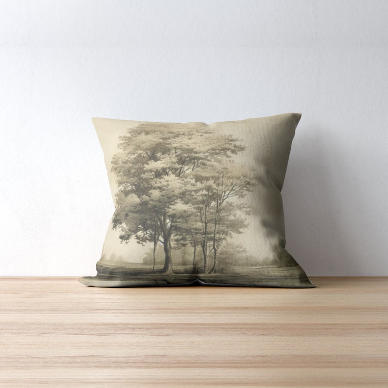 May include: A throw pillow featuring a sepia-toned image of a group of trees in a field. The pillow is made from a light brown fabric.