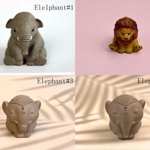 May include: Four small ceramic animal figurines: a gray elephant, a gray elephant with a red dot on its forehead, a gray elephant with a red dot on its forehead, and a brown lion. The elephants are in a sitting position, while the lion is sitting with its paws outstretched. The figurines are on a variety of surfaces, including a white surface, a pink surface, and a brown surface.