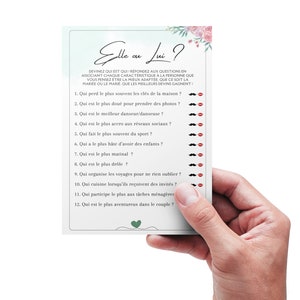 May include: A light blue card with pink floral accents and the text "Elle ou Lui?"  The card features a list of 12 questions to help couples learn more about each other.
