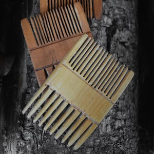 May include: Three wooden combs of different sizes and styles. The combs are made of light and dark wood and have a natural finish. The combs are arranged on a textured wooden surface. The text "S&D Alania Workshop" is visible in the upper right corner of the image.