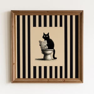 Könnte beinhalten: Ein gerahmter quadratischer Druck, der eine schwarze Katze zeigt, die auf einer Toilette sitzt und eine Zeitung liest. Die zentrale Illustration ist auf beigem Hintergrund platziert, umgeben von vertikalen schwarz-weißen Streifen in einem Holzrahmen.