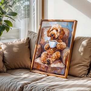 May include: A framed artwork showing a brown Goldendoodle dog in a chair, holding a white coffee cup. The dog is the central figure, with a soft, fluffy appearance. The artwork is set against a neutral background, with a wooden frame.