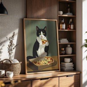 May include: A framed art print featuring a tuxedo cat enjoying a slice of pizza. The cat is black and white with green eyes, holding the pizza slice. The pizza is in a cardboard box, and the background is a muted green.