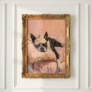 May include: A framed painting of a Boston Terrier dog wearing a sleep mask, resting on a pink pillow. The dog is black and white, with its head and paws visible. The ornate gold frame adds a touch of elegance to the artwork.