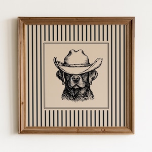 May include: A framed print with a black and white illustration of a dog wearing a cowboy hat. The artwork is set against a beige background with a black and white striped border, in a wooden frame.