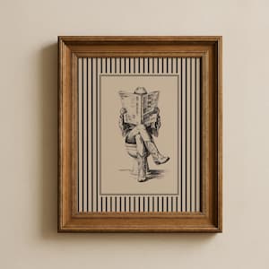 May include: A framed wall art print featuring a black and white ink illustration of a figure wearing a cowboy hat and boots, sitting on a toilet whilst reading a newspaper. The artwork is set against a tan background with black vertical stripes.