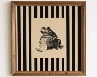 May include: A square framed wall art piece featuring a black and white illustration of a toad holding a roll of toilet paper. The central image is set against a background of vertical black and beige stripes, all enclosed in a wooden frame.