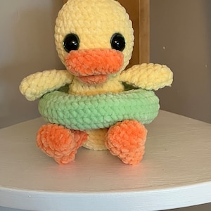 Peut inclure: Un canard jaune en crochet avec des pieds et un bec orange, portant un gilet de sauvetage vert en crochet.