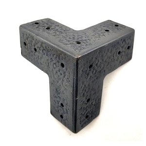 Puede incluir: Una escuadra de esquina de metal negro con múltiples agujeros para sujetar muebles u otras estructuras. La escuadra tiene una superficie texturizada y un diseño de tres vías.
