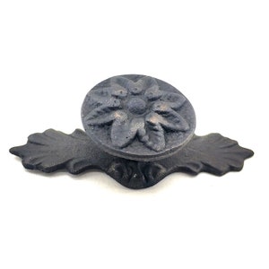 May include: Black cast iron drawer pull with a floral design. The pull has a round knob and a decorative base.