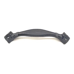 Op de afbeelding: Een zwarte, decoratieve kastgreep met een gebogen handvat. De greep heeft een licht getextureerd oppervlak en wordt geflankeerd door sierlijke, ruitvormige uiteinden met geboorde gaten voor montage. De hardware is van metaal.