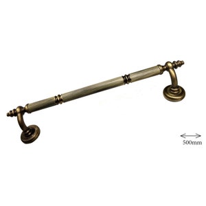 May include: An antique bronze-colored door pull with a ribbed center section and decorative end pieces. The handle is approximately 500mm in length, with a curved support and circular base on each end. Ideal for vintage-style doors.