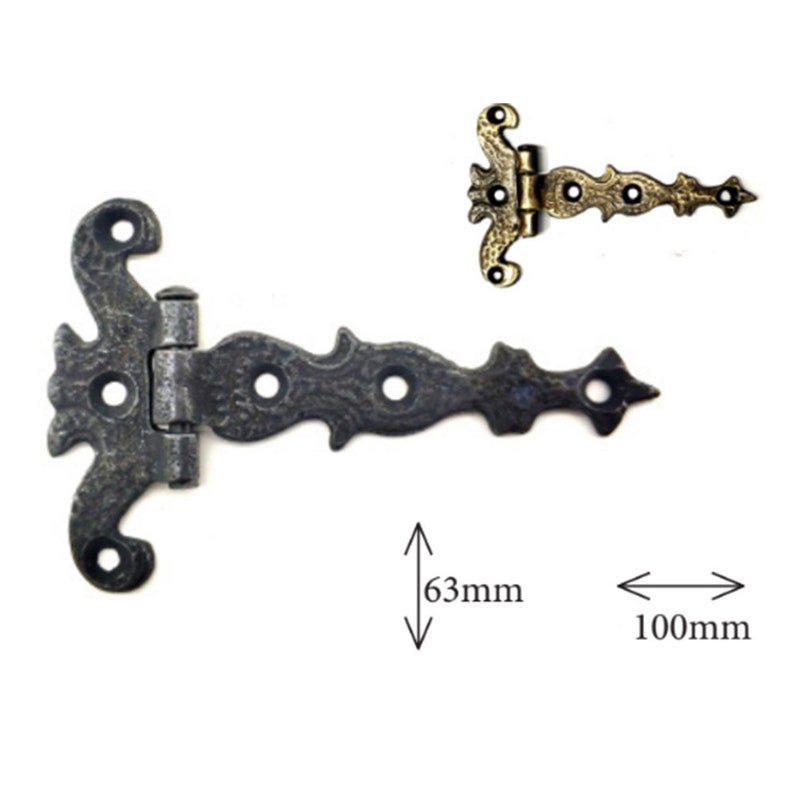 Puede incluir: Bisagra en T ornamentada de estilo antiguo, con un acabado oscuro y envejecido. La bisagra mide 10 cm de largo y 6,3 cm de alto, con volutas decorativas y tres orificios pretaladrados. Tambi&eacute;n se muestra una bisagra m&aacute;s peque&ntilde;a, dorada.