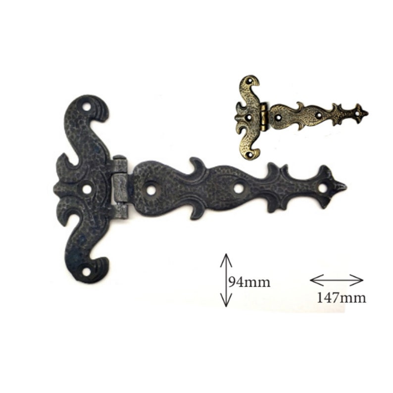 Puede incluir: Bisagra de metal negro ornamentada con volutas decorativas y un acabado envejecido. La bisagra mide 147 mm de largo y 94 mm de ancho. Se muestra una bisagra m&aacute;s peque&ntilde;a y similar arriba. Ideal para decoraci&oacute;n r&uacute;stica o vintage.