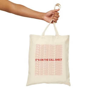 May include: A white canvas tote bag with the phrase "IT'S ON THE CALL SHEET" repeated in red text.
