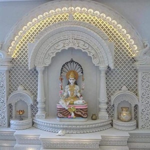 Peut inclure: Un autel hindou en marbre blanc avec des sculptures complexes et une statue d'une divinité. L'autel est doté d'une arche décorative et d'une base à plusieurs niveaux. La divinité est assise sur un trône et porte une couronne et des bijoux.