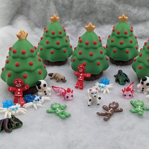 May include: A set of six miniature Christmas trees with red and green ornaments, surrounded by various small figurines, including gingerbread people, snowmen, and a platypus.