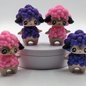 May include: Four small, hand-painted sheep figurines. Two are purple and two are pink. Each sheep has a fluffy, textured coat and black eyes.