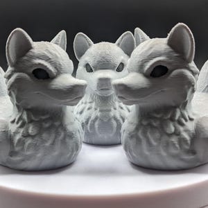 May include: Three white ceramic wolf duck figurines. The ducks have a detailed design with a wolf head and a duck body.