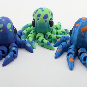 May include: Three small octopus figurines with different color patterns. The octopus on the left is blue with green spots, the middle octopus is green with blue spots, and the octopus on the right is blue with orange spots.