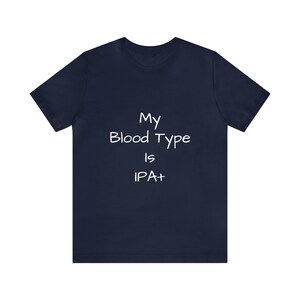 Puede incluir: Una camiseta azul marino con texto blanco que dice "My Blood Type Is IPA+"