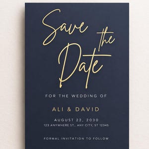 Op de afbeelding: Marineblauwe trouwkaart met gouden tekst. De tekst luidt "Save the Date" in elegant schrift, gevolgd door de namen Ali & David, de datum en het adres. De woorden "Buy, Edit, Download" staan bovenaan.