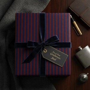 May include: A wrapped gift box with a navy blue velvet ribbon and bow. The gift wrap has vertical stripes in navy blue and red. A tag reads "For a True Gentleman, Joel."