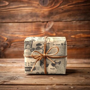 May include: A brown gift box wrapped in vintage newspaper print featuring a black and white illustration of a horse and rider. The box is tied with twine and has the text "Roy Rogers" printed on the front.