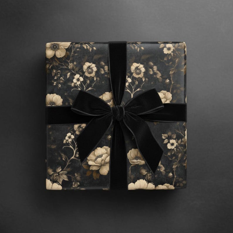 May include: A wrapped gift box featuring floral patterned wrapping paper in black and cream. A wide black velvet ribbon is wrapped around the box and tied into a bow. The background is a solid black.