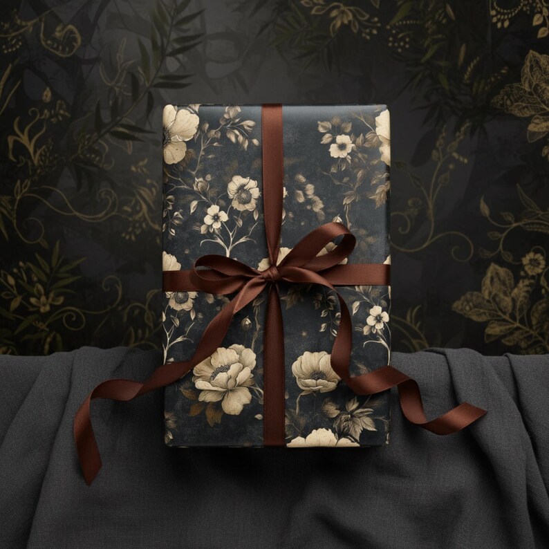 May include: A wrapped gift box featuring a dark blue floral pattern with cream-colored flowers and foliage. The box is tied with a brown satin ribbon, creating a bow. The background is a dark, patterned surface, suggesting a decorative or artistic theme.