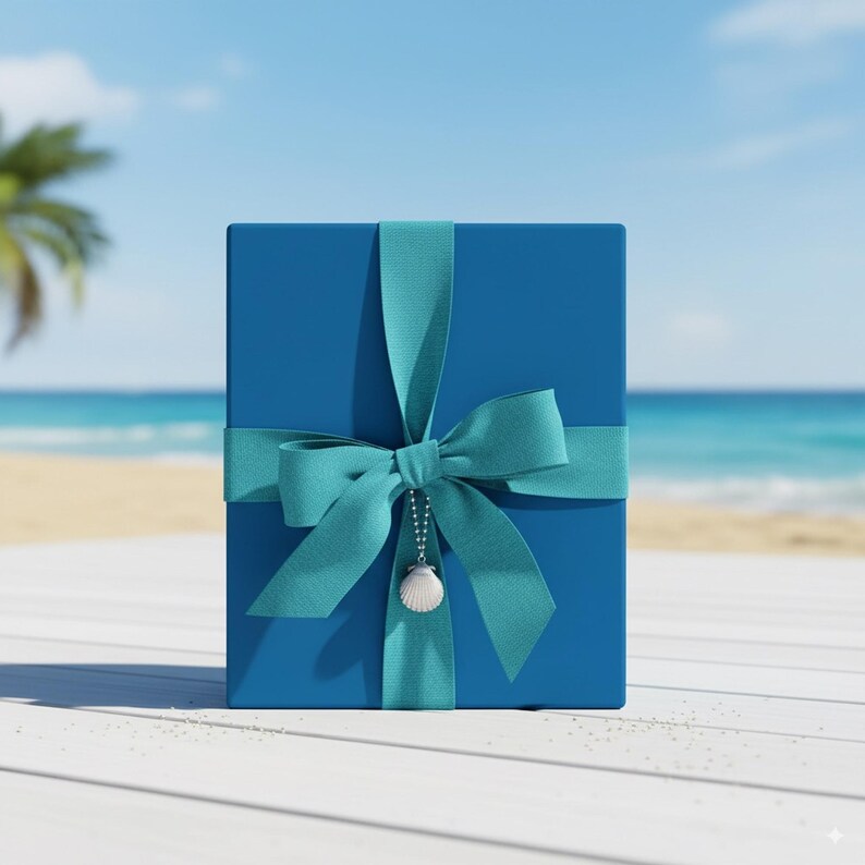 Op de afbeelding: Een blauwe geschenkdoos, vastgebonden met een turquoise lint en strik. Een kleine schelpenbedel hangt aan de strik. De achtergrond toont een strandsc&egrave;ne.